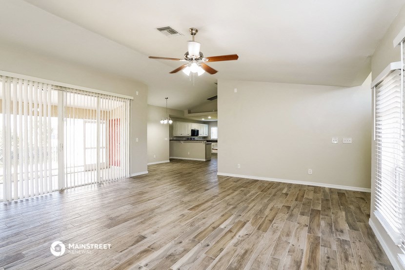 an empty living room with wood flooring and a ceiling fan