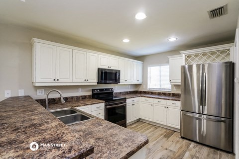 a kitchen with white cabinets and a stainless steel refrigerator