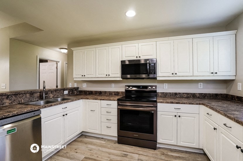 a kitchen with white cabinets and black appliances