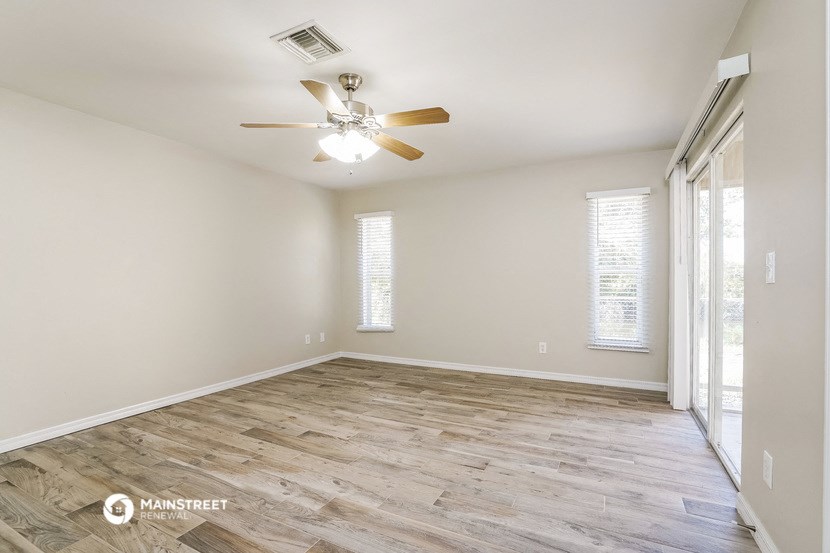 the spacious living room with wood flooring and a ceiling fan