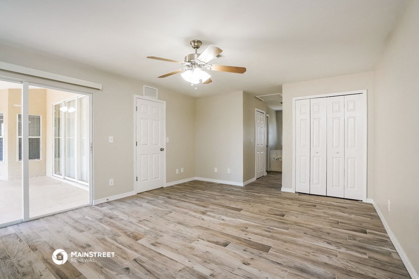 a spacious living room with wood flooring and a ceiling fan