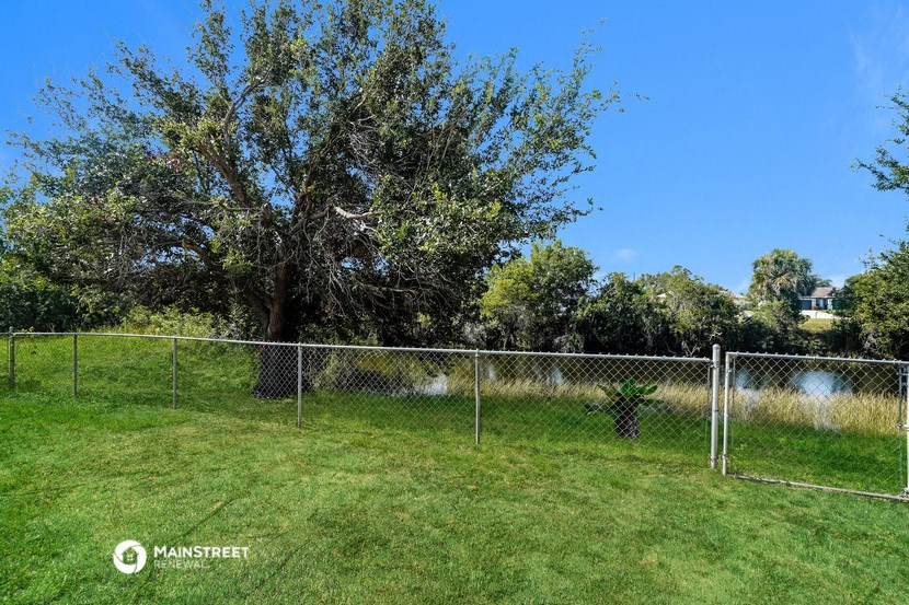 a tree in a field behind a chain link fence