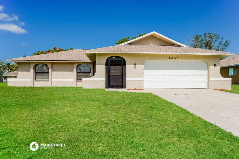 a beige house with a lawn and a white garage door