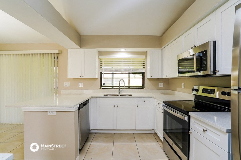 a kitchen with white cabinets and black appliances and a window