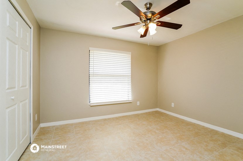 an empty room with a ceiling fan and a window