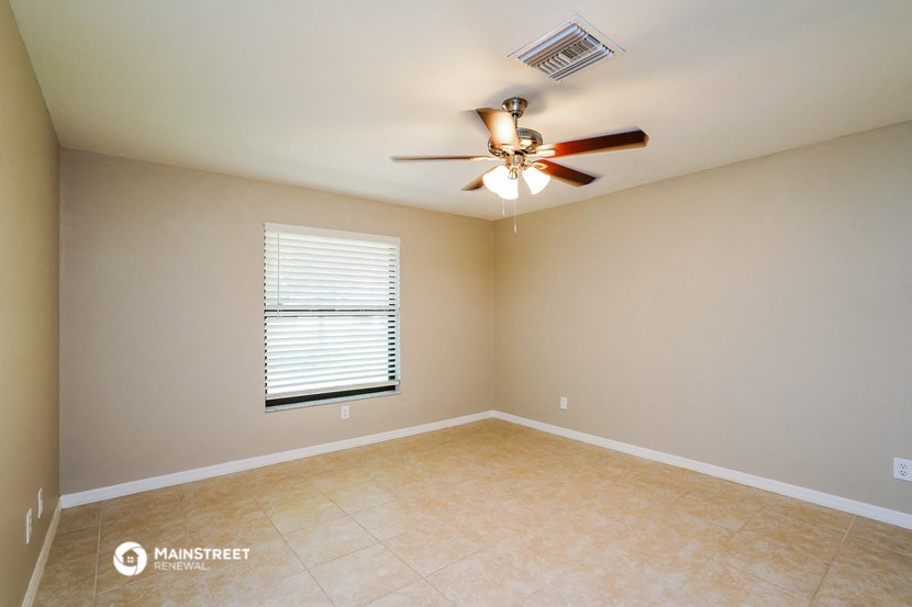 an empty living room with a ceiling fan and a window