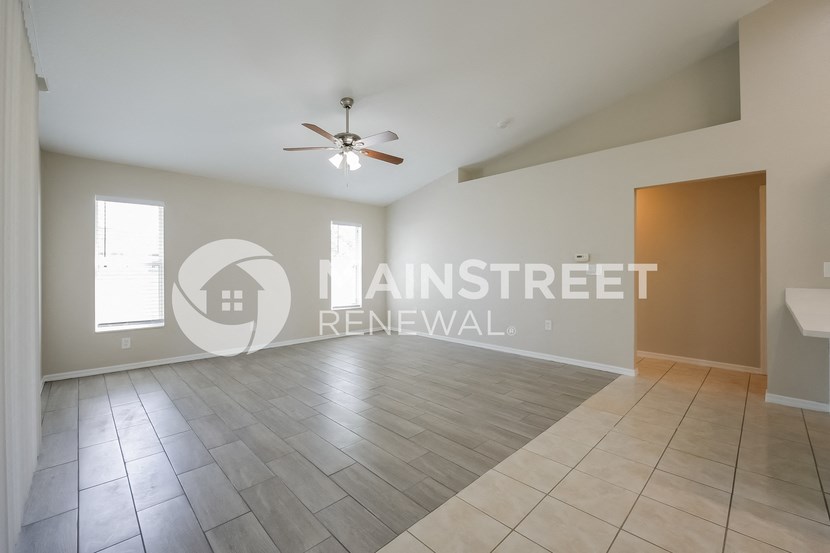 a large living room with tile floors and a ceiling fan