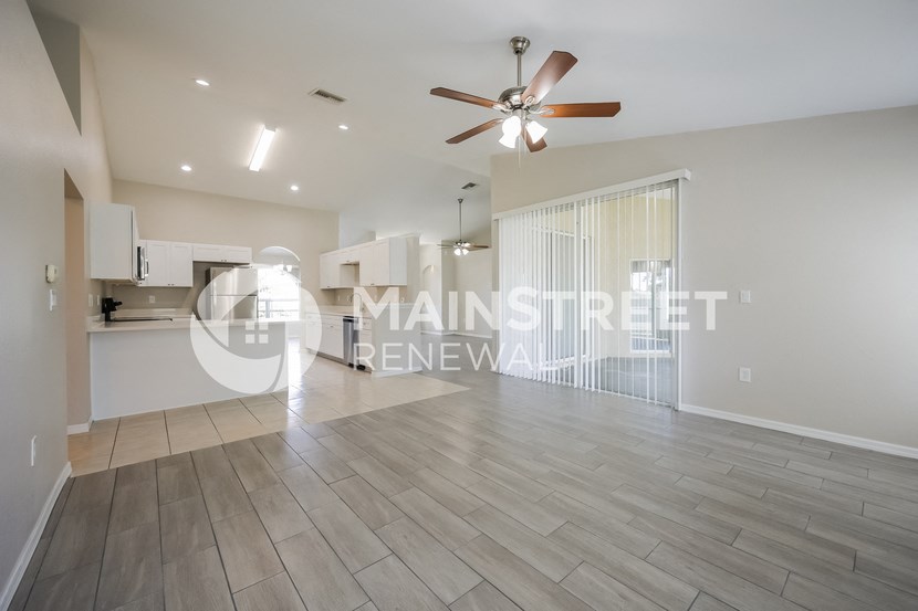 a large living room with a ceiling fan and a kitchen