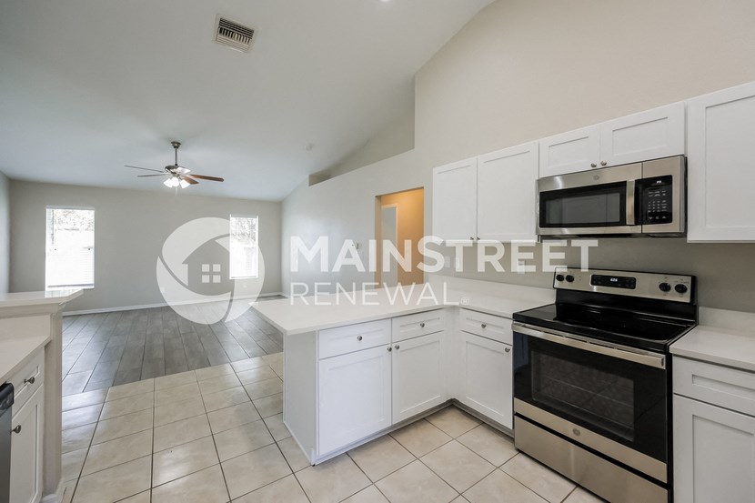 a renovated kitchen with white cabinets and stainless steel appliances