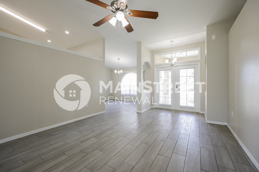 a renovated living room with hardwood floors and a ceiling fan