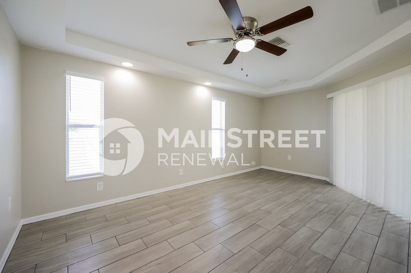 an empty living room with a ceiling fan and a window