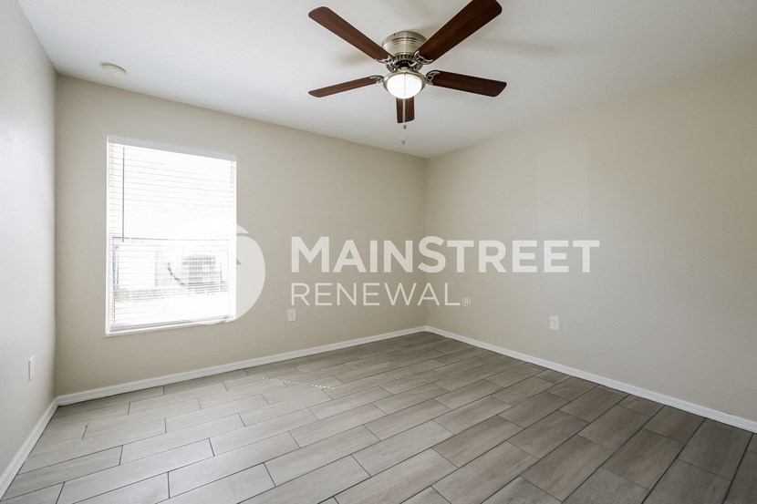 an empty room with a ceiling fan and a window