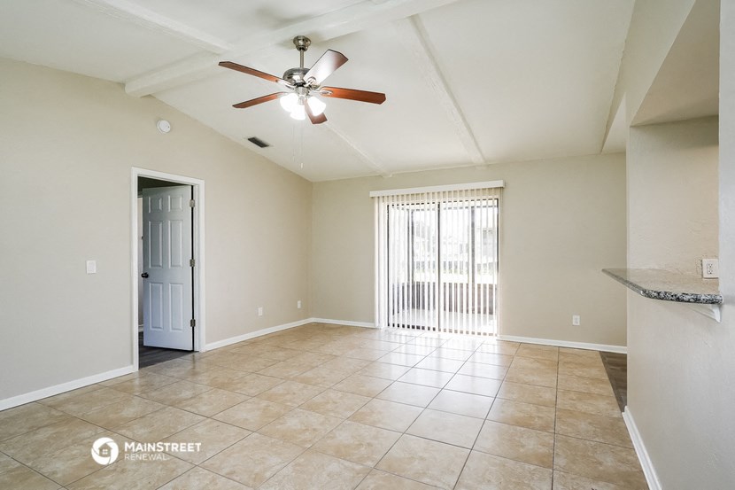 an empty living room with a ceiling fan