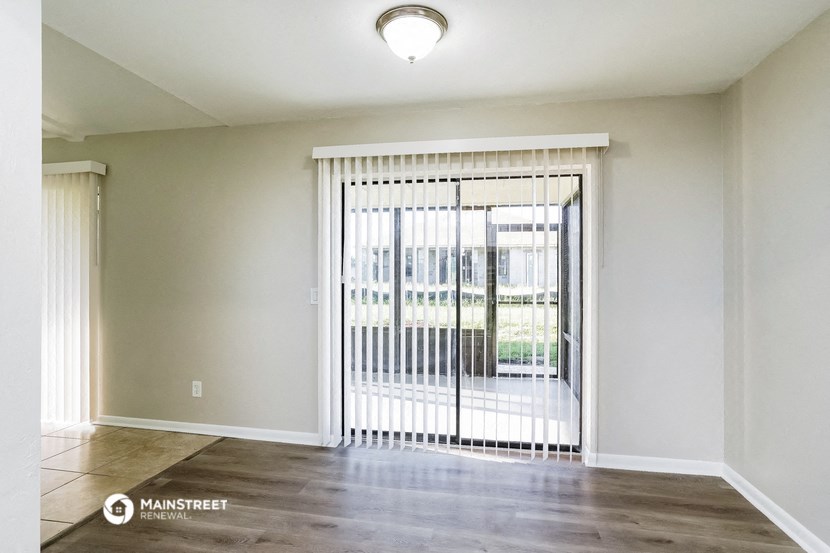 an empty living room with a sliding glass door to a balcony