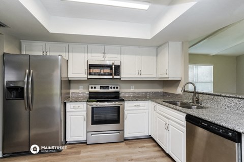 a kitchen with white cabinets and stainless steel appliances