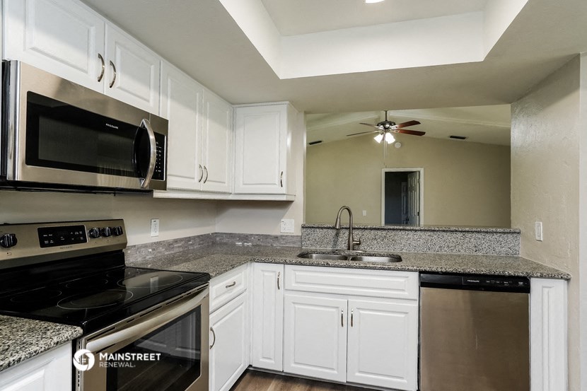a kitchen with granite counter tops and white cabinets