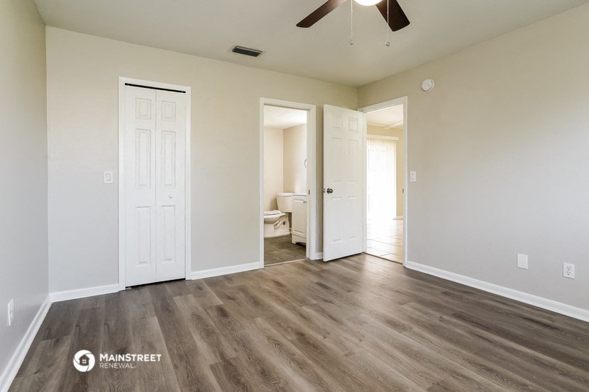 an empty living room with wood floors and a ceiling fan