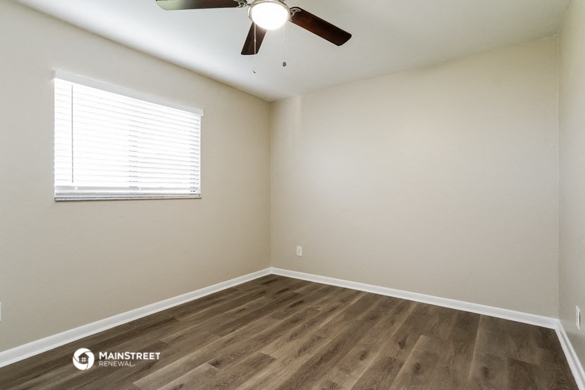 the spacious living room with wood floors and a ceiling fan