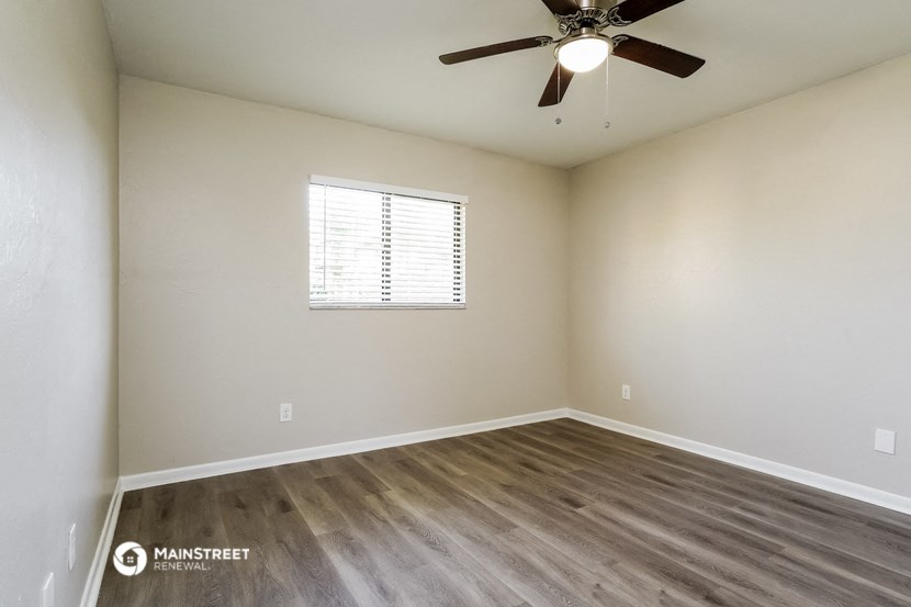 the spacious living room with wood flooring and a ceiling fan