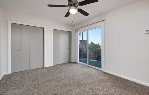 an empty living room with a ceiling fan and a window