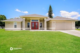 a large lawn in front of a house with a red door