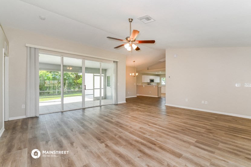 an empty living room with a ceiling fan and sliding glass doors