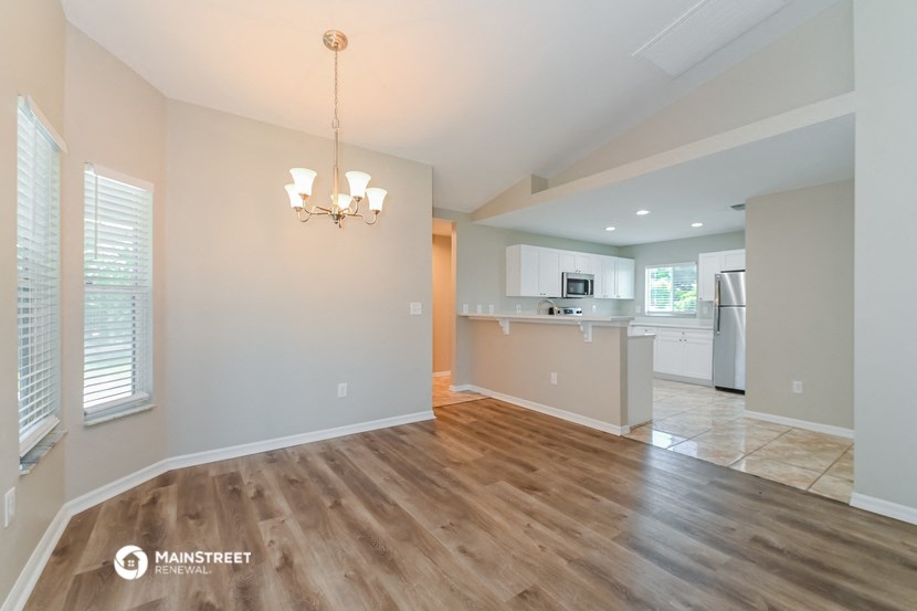an empty living room with a kitchen in the background