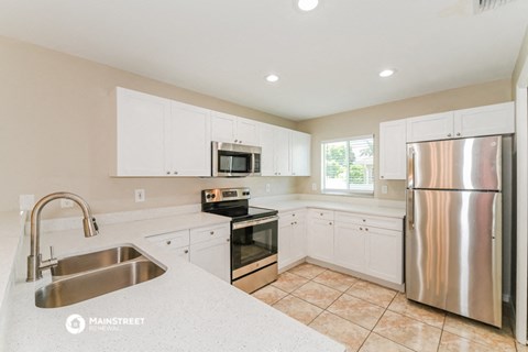 the kitchen has stainless steel appliances and white cabinets