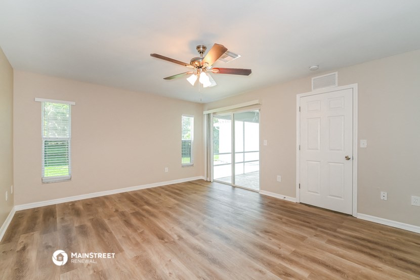 the spacious living room with wood floors and a ceiling fan