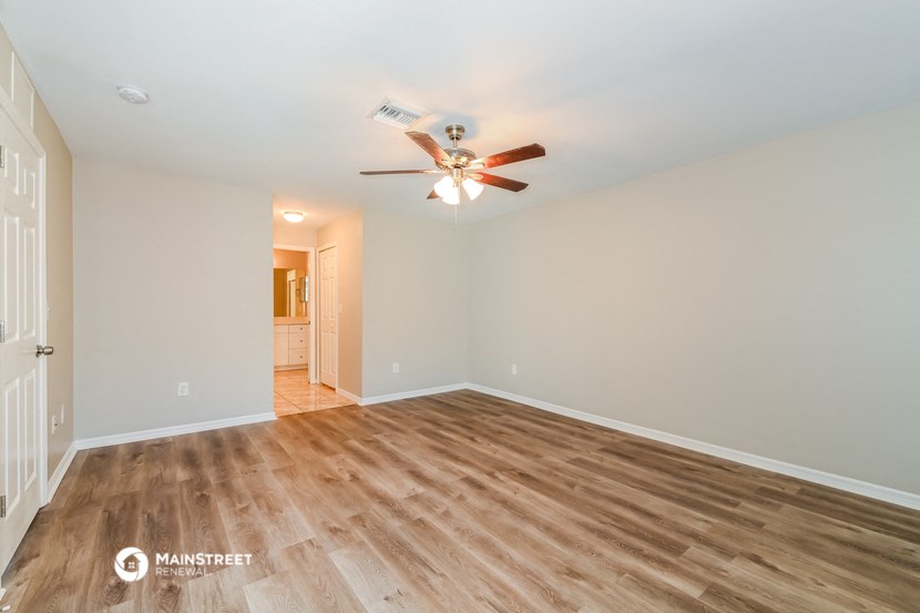 the spacious living room with wood flooring and a ceiling fan