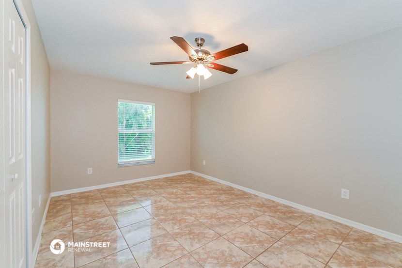 the spacious living room has a ceiling fan and tile flooring