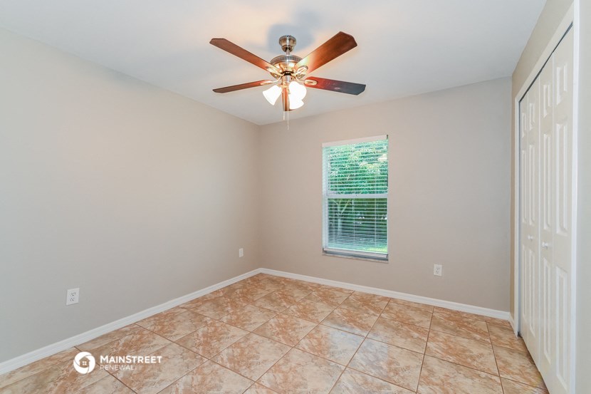 the living room has a ceiling fan and tile flooring