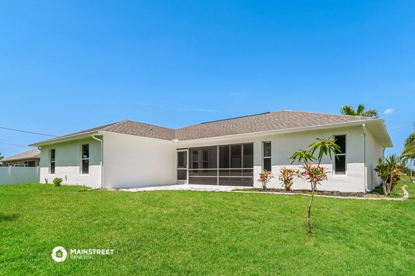 a white house with a lawn and a palm tree