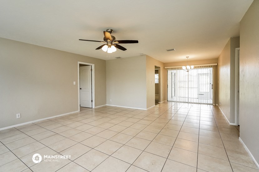an empty living room with a ceiling fan and tiled floors