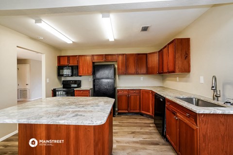 a kitchen with wooden cabinets and granite counter tops and a black refrigerator