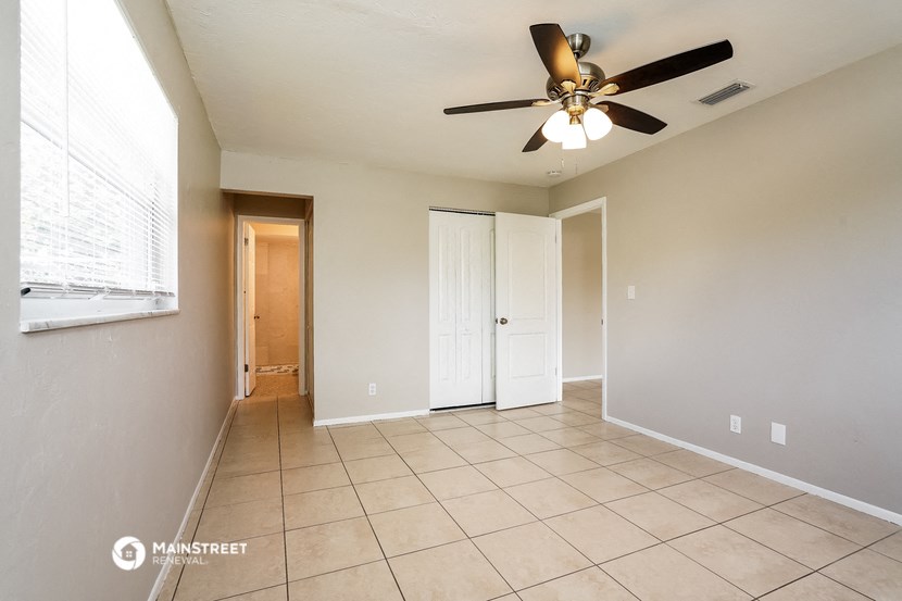 an empty living room with a ceiling fan and tiled floors