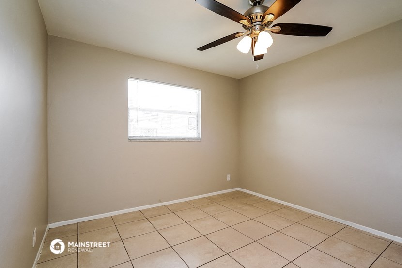 an empty living room with a ceiling fan and a window