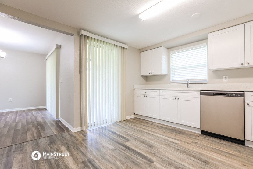 an empty kitchen with white cabinets and wood flooring