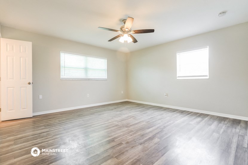 the spacious living room with wood floors and a ceiling fan