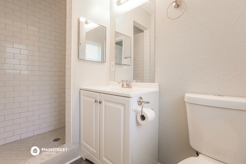 a white bathroom with a toilet and a sink and a mirror