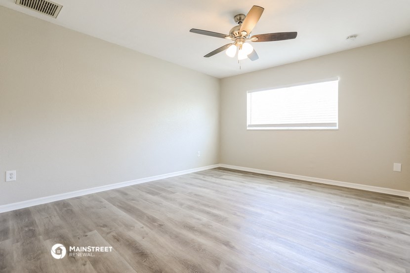 an empty living room with a ceiling fan and a window