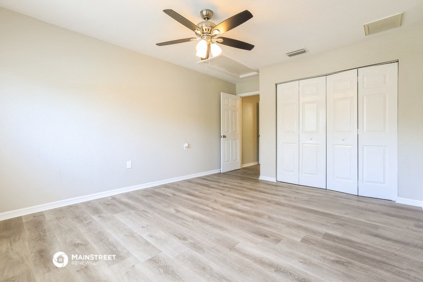 an empty living room with white walls and a ceiling fan