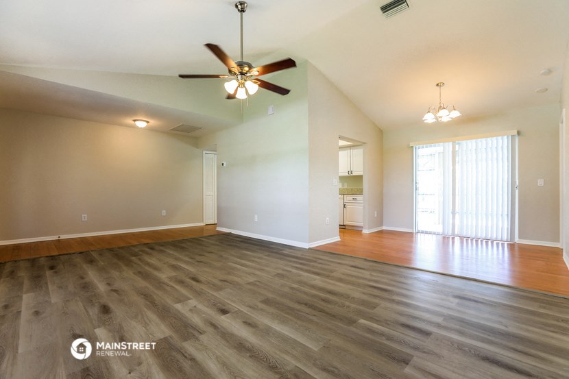 an empty living room with wood floors and a ceiling fan