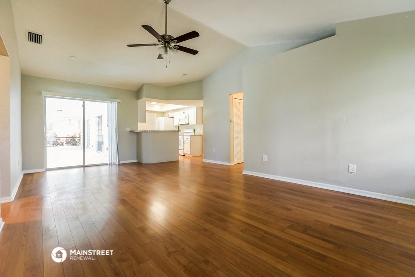 an empty living room with wood floors and a ceiling fan