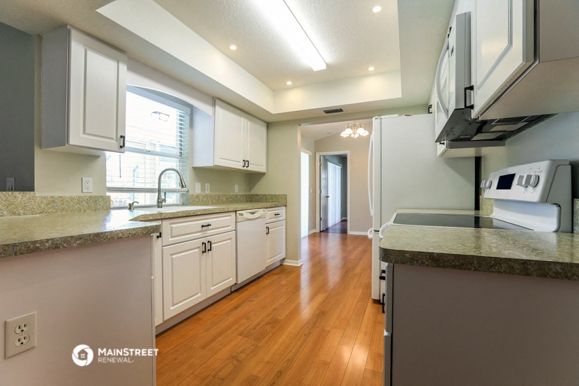 a large kitchen with white cabinets and a wood floor