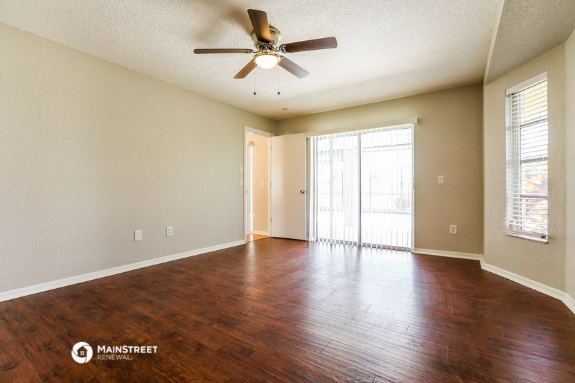 an empty living room with wood floors and a ceiling fan
