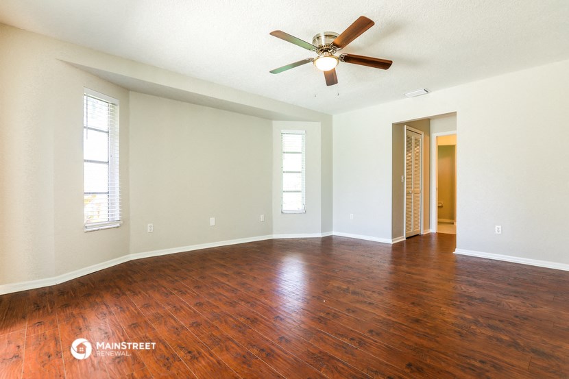 an empty living room with wood floors and a ceiling fan