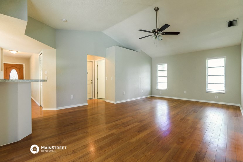 an empty living room with wood floors and a ceiling fan