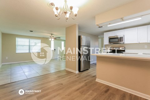 a renovated kitchen with a large island and a stainless steel refrigerator