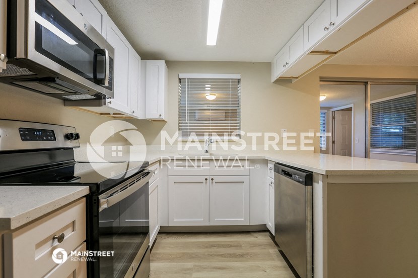 a renovated kitchen with white cabinets and black appliances
